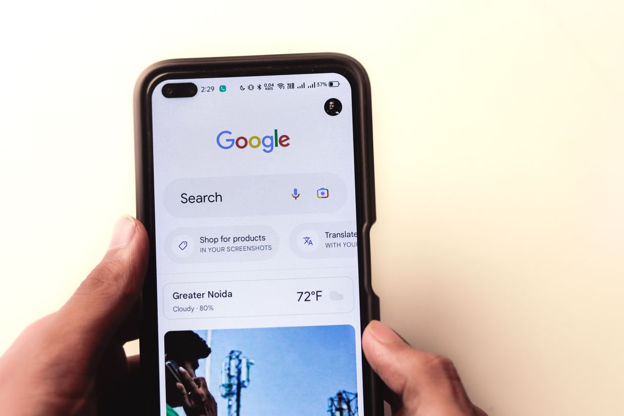 services-01 A tight close-up shows a hand holding a smartphone, with the Google search page visible on the screen.